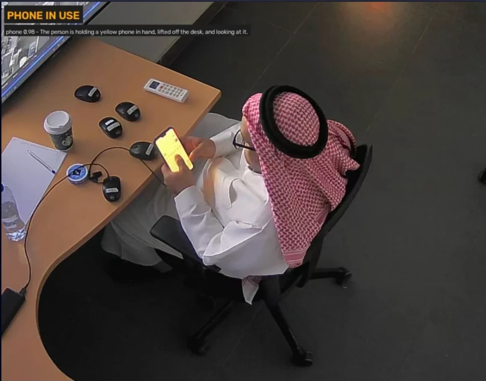 AI detection view flagging phone use at a control-room desk with a confidence score and description